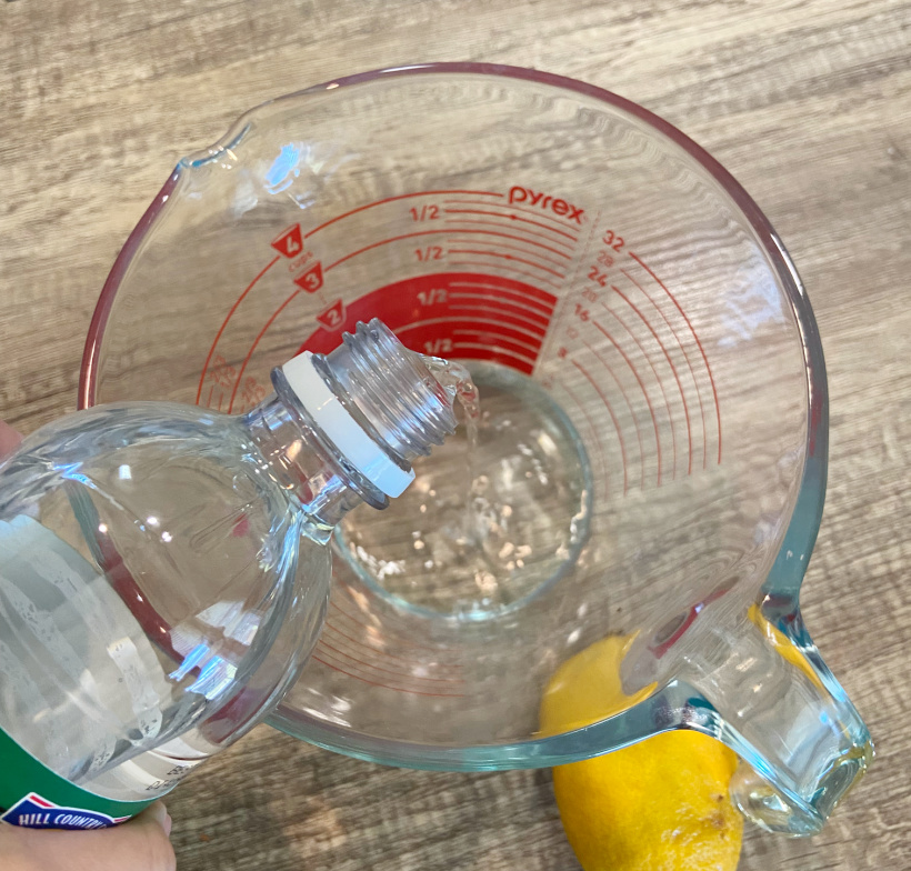 adding vinegar to a bowl with homemade microwave cleaner